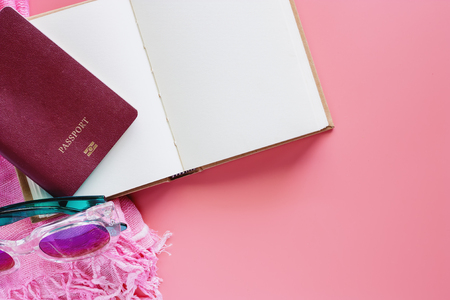 Passport with opened notebook, sunglasses and scarf on pink background for travel concept. Flat lay and top view image.の写真素材