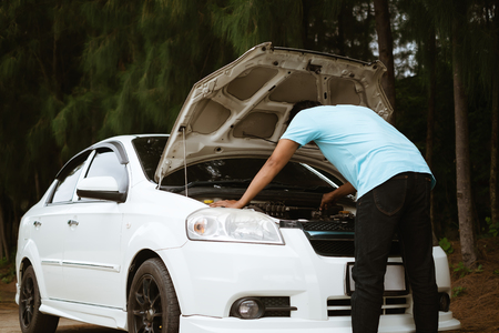 Stressed asian man looking at the engine of broken car for transportation and vehicle conceptの写真素材