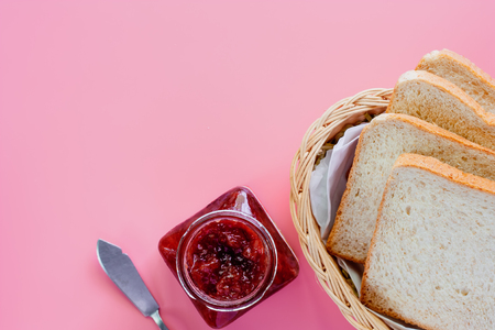Sliced fine whole wheat bread with strawberry spread on pink background for food and eating conceptの写真素材