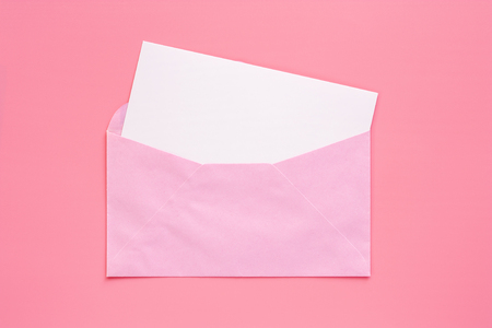 Pink envelope with blank white greeting paper card on pink backgroundの写真素材