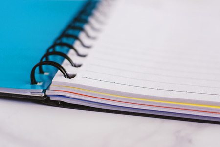 Spiral blank notebook on white marble background for office and school supplies concept, selective focus and DOFの写真素材