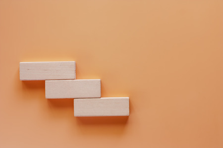 Wooden toy staircase on beige color background for step to goal success conceptの写真素材
