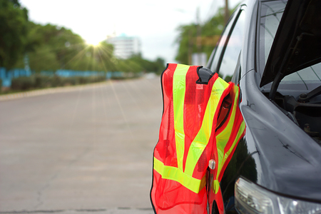 Reflective mesh safety vest with broken car on the road for vehicle and transportation conceptの写真素材