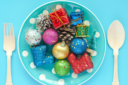 Polka dot plate of Xmas ornaments and decoration with wooden spoon and fork on blue background for...