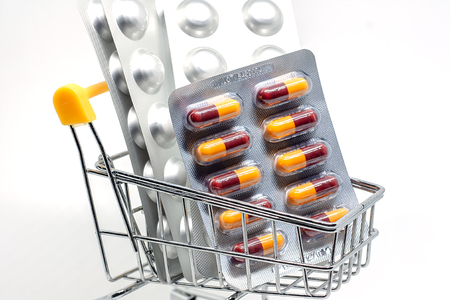 Medicine, pills, drug or tablets in a blister pack in shopping cart on white background for healthcare and medical conceptの写真素材