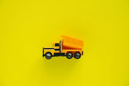 Mini toy dump truck on yellow background for vehicle and transportation conceptの写真素材