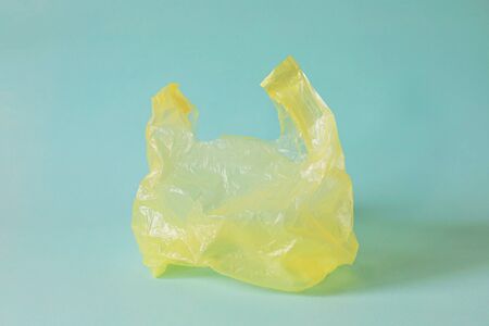 Empty yellow plastic bag against light blue background for waste recycling conceptの写真素材