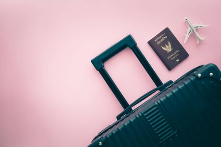 Black luggage, Thai passport and white airplane model on pink background for travel and journey conceptの写真素材