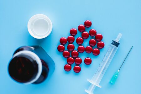 Blood tonic includes multivitamins, folic acid, and iron liquid with bottle and syringe injection on blue background for healthcare and medical conceptの写真素材