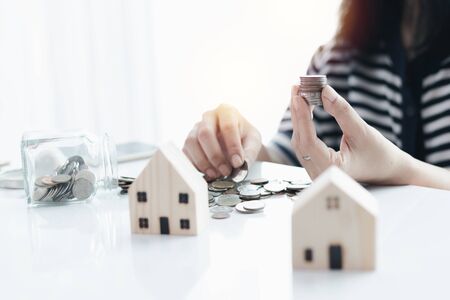 Woman's hand saving a coin for planning, housing and property financial conceptの写真素材