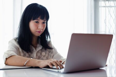 Asian woman using laptop and working at home for businessの写真素材