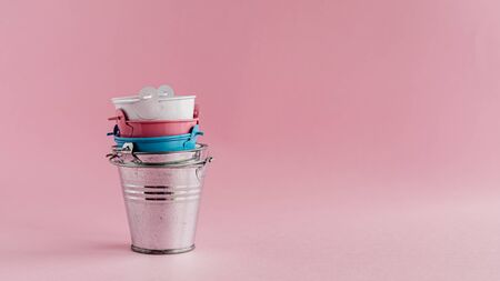 Mini colored tin pails or buckets on pink background with copy spaceの写真素材