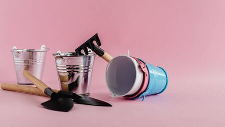 Gardening tools with tin pails or buckets on pink background for planting conceptの写真素材