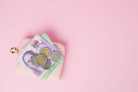 Thai currency banknote and money coins with wallet on pink background for business, finance,...