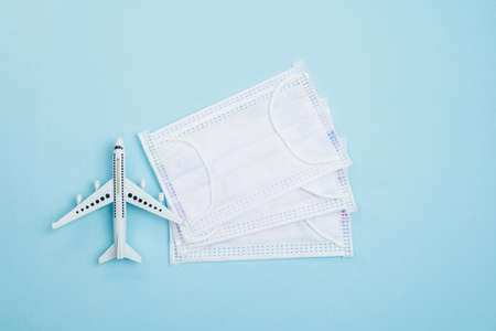 White airplane model with hygiene face mask on blue background for travelling and healthcares...