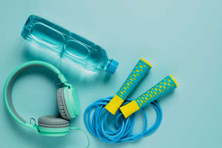 Fresh drinking water, jump rope and headphones on blue background for sports and healthcare conceptの写真素材