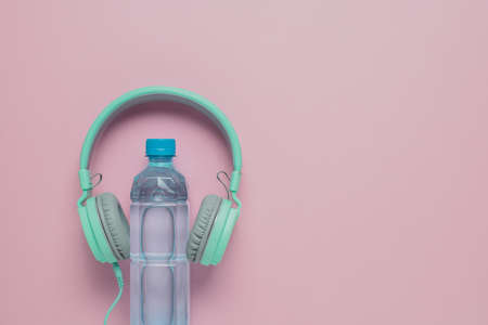 Fresh drinking water with headphones on pink background for healthcare and relaxation conceptの写真素材