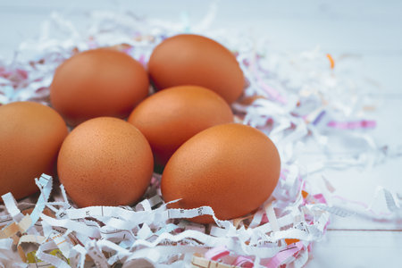 Eggs in the shredded paper on white wooden background for healthy food concept