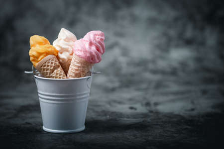 Various of colourful meringue ice cream cone in the bucket on dark background for sweet and refreshing dessert conceptの写真素材