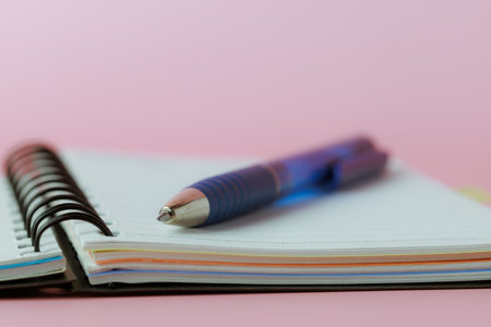 Selective focus of a pen on a notebook against pink background for the concept of work and study.の写真素材