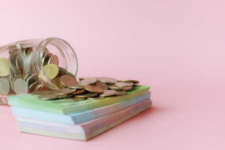 A glass jar of coins with banknotes on pink background for the concept of business and finance.の写真素材