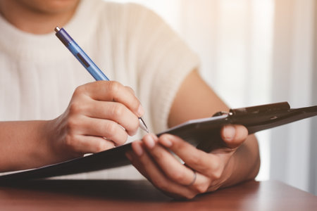 Asian woman's hand holding a pen and writing something on the notebook for the concept of work and...