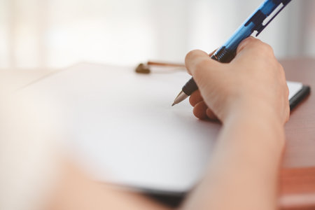 Asian woman's hand holding a pen and writing something on the notebook for the concept of work and study.の写真素材