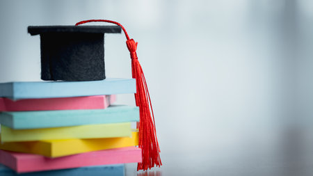 Graduation cap on stack of sticky notes. Concept of education, back to school, study planning, academic success, reminders, and student organization.の写真素材