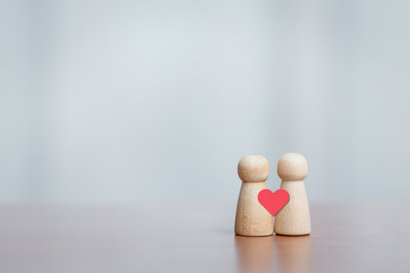 Two wooden figures with heart symbol. Concept of love, connection, relationship, empathy, care, and emotional bonding.の写真素材
