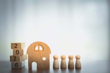 Wooden house with peg figures and 2026 blocks. Concept of home, family, future plans, real estate...