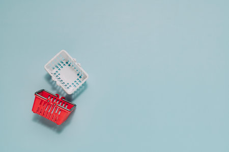 Red and white miniature shopping baskets on light blue. Perfect for themes of retail, consumerism,...