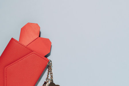 Red wallet with a hidden red heart and keychain on soft blue background. Perfect for themes of love,...