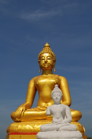 A golden and white buddha statue sits in peaceful meditationの写真素材