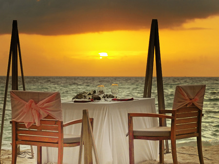 Dining table on the beach during sunsetの写真素材