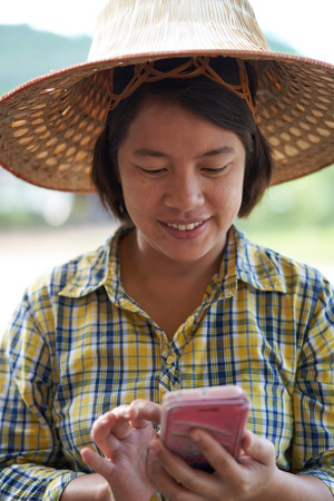portrait female smart farmer using smartphone in blur rice field and mountain background. concept  is mordern smart farming,high tech farming, highly educated.の写真素材
