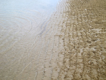 Wave sand with crab hole and sea water separated in halfの写真素材