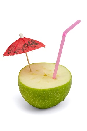 Close-up of green apple with a straw and umbrella, isolated on whiteの写真素材