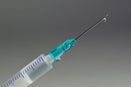 A macro shot of a hypodermic needle with a droplet of fluidの写真素材
