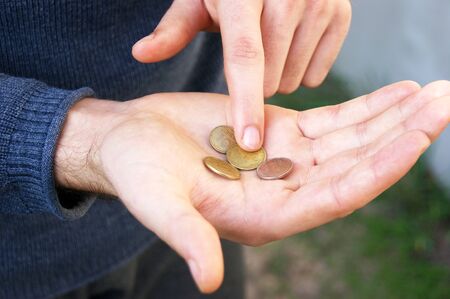 Hands of a young man close-up, counting a trifle, iron coins money of Ukraine. The concept of a...