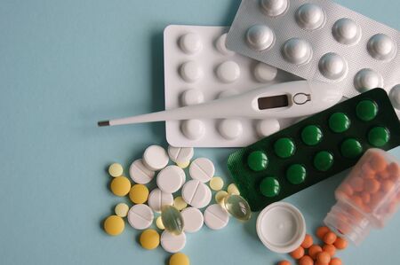 Assorted pharmaceutical medicine pills, tablets and capsules on blue background. Maintenance of...