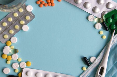 Assorted pharmaceutical medicine pills, tablets and capsules on blue background. Maintenance of...