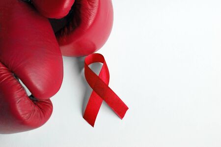 Close-up of red boxing gloves and ribbons isolated on white, symbolizing the fight against aids or hiv.の写真素材