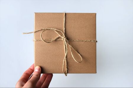 Girl holds out a gift craft box. Surprise. White background.
