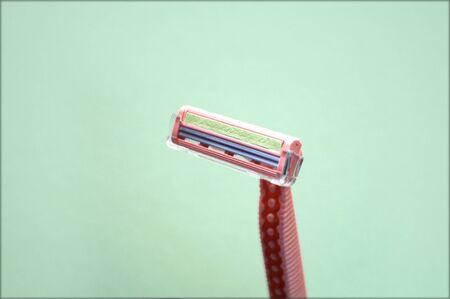 Closeup view with selective focus of disposable shaver isolated on abstract green background. Man and woman body treatment of depilation with razor and skin care concept. Epilation hair removal.の写真素材