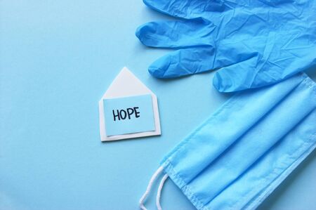 A three-layer medical mask with rubber ear straps, white paper home and blue stiker with the word...