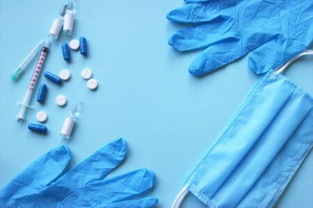 A three-layer medical mask with rubber ear straps and various medicines, tablets, vaccines. The...