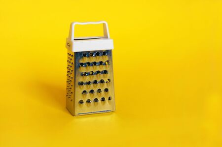 Grater stainless steel closeup on yellow background.の写真素材