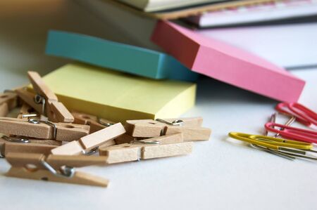 Small office supplies randomly lie on the desktop. Stickers, paper clips, pins, notebook.
