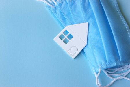 A three-layer medical mask with rubber ear straps, white paper home. The concept of medicine. Hope. Stay home, stay safe.の写真素材