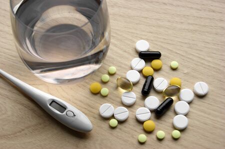 Closeup flat-lay electronic thermometer and medicine color white, orange, yellow and black pills. Shot from above and selective focus. Top viewの写真素材